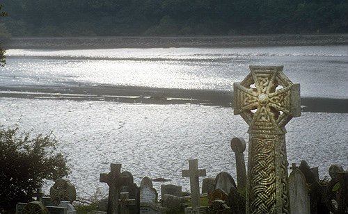 Ancient crosses and grave stones against sunlight on Fowey estuary, St Winnow, Cornwall, England