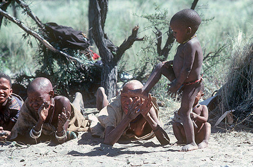 Bushman boy Gae-tebe dancing and women clapping, Kalahari, Southern Africa