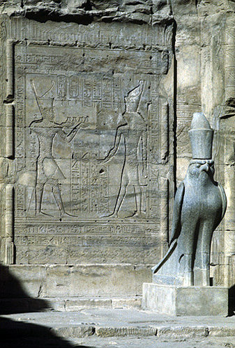 Egypt, Edfu, Temple of Horus, relief of Ptolemy giving gifts to the falcon god Horus, beside a black granite statue of Horus
