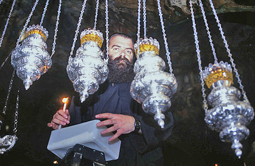 Israel, Jerusalem,  a Greek- Orthodox priest tends the oil lamps at the twelfth Station of the Cross