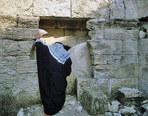 Israel, an Arab peering into a tomb with a rolling stone like Jesus