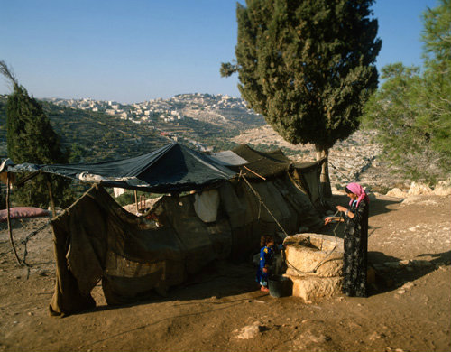 Israel, Bedouin woman at a well by her tent, Bethlehem in the background