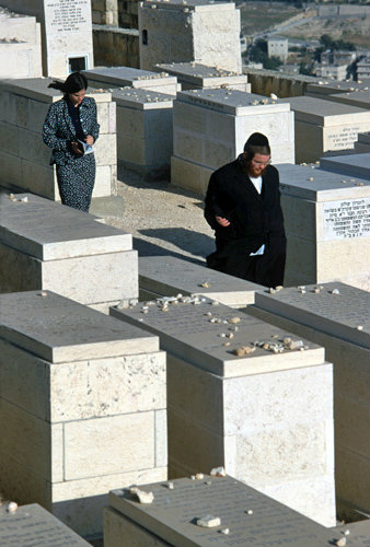 Israel Jerusalem Orthodox Jews pass by graves in the Jewish Cemetery on the Mount of Olives