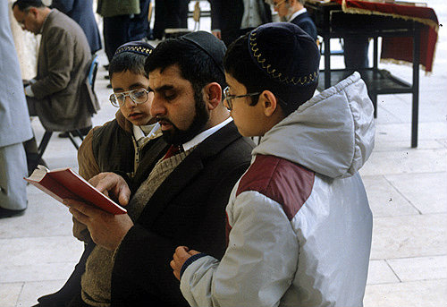 Israel, Jerusalem, Jewish father with his sons reading the prayer book near the Western Wall