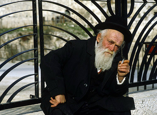 Israel, Jerusalem, an Orthodox Jew sitting on a wall smoking and passing the time of day