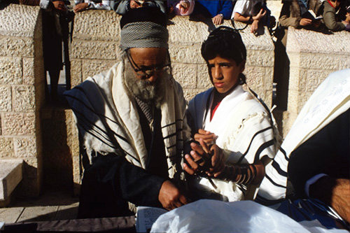 Israel Jerusalem Sephardic Rabbi holding the boys hand while they pray together at the Bar mitzvah ceremony