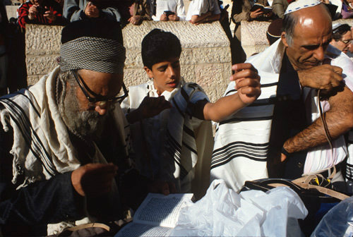 Israel Jerusalem Sephardic Jewish Rabbi with father and son putting on their tefillin at the son