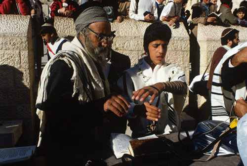 Israel Jerusalem Sephardic Rabbi helping boy put on the tefillin at his Bar mitzvah