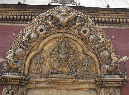 Kali, fierce aspect of Goddess Duga (Parvati), in centre, flanked by two nymphs, carving on top of Golden Gate, Bhaktapur, Nepal