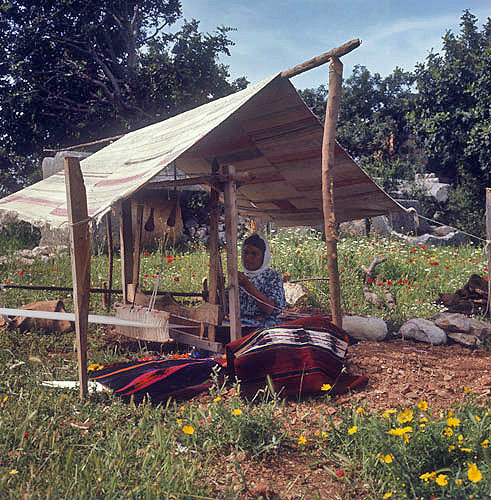 Nomad woman weaving a kilim in a clearing amongst Roman sarcophagi, Cilicia, south Turkey