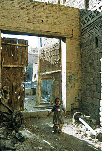 Child beside doorway of house in Sana