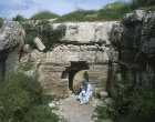 Arab sitting outside tomb with rolling stone, similar to that of Christ, south west of Hebron, Israel