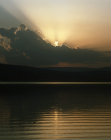 Setting sun behind a cloud reflected in the Sea of Galilee, Israel