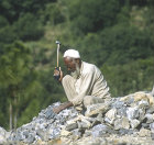 Pakistan, man breaking up stones for road making